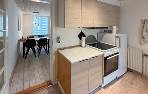A compact kitchen with a stove, oven, and a dining area with chairs and a table. - Lovely home in Aabenraa with WiFi (Aabenraa)