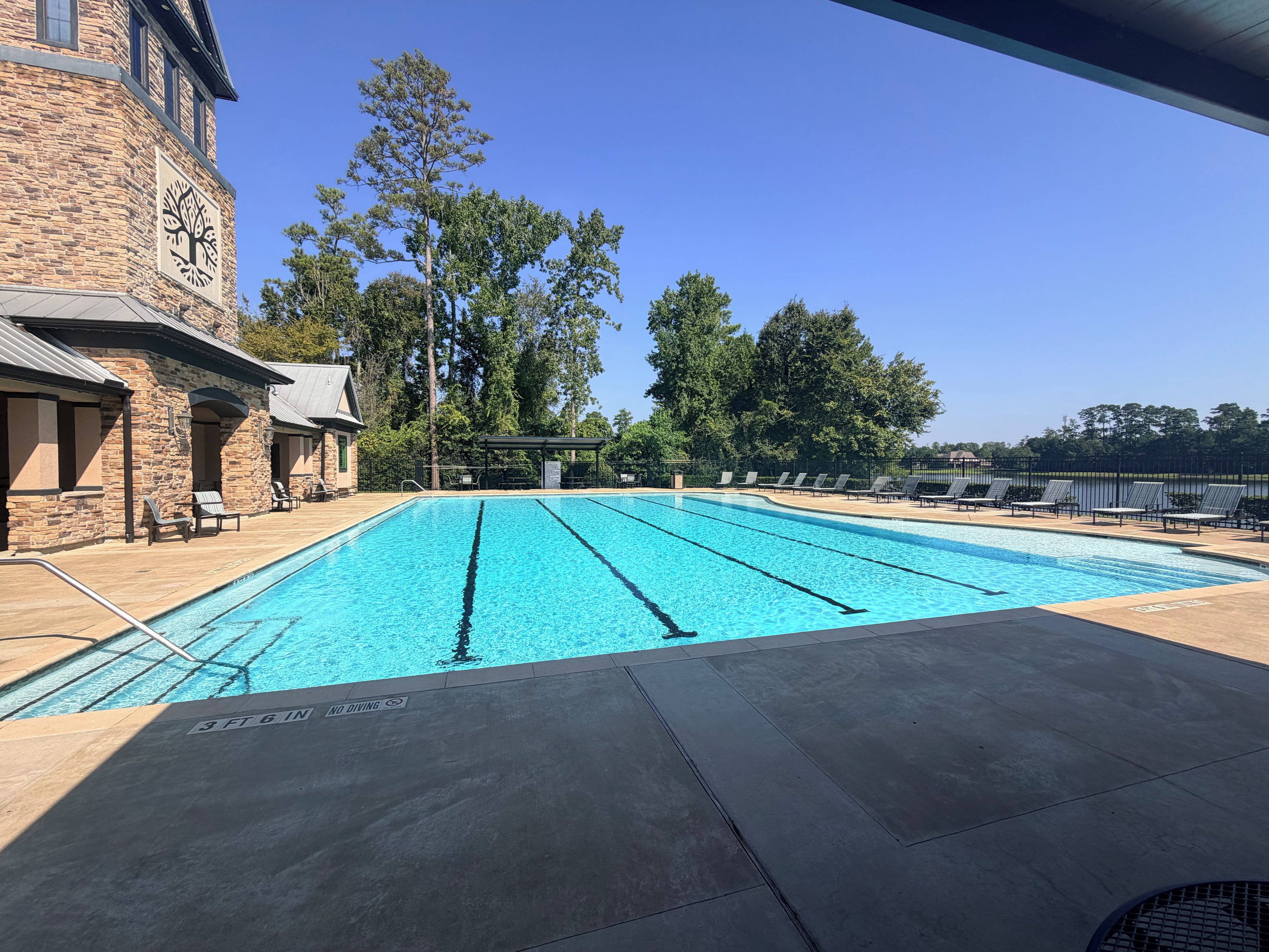 A swimming pool with lounge chairs and a stone building in the background.