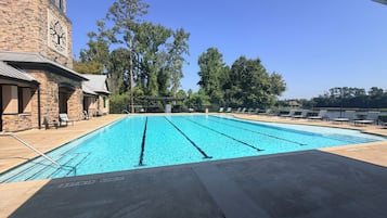 A swimming pool with lounge chairs and a stone building in the background.