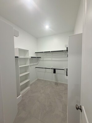Quarto com paredes brancas, piso de azulejos e porta com puxador prateado.