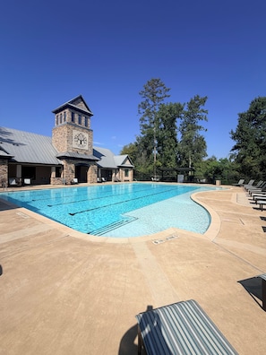 A swimming pool with a stone building and a clock tower in the background.