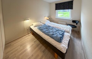 A bedroom with two beds, a window with a view, a chair, and a desk. - Nice home in Gråsten with sauna (Gråsten)