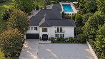 A two-story house with a front yard, a swimming pool, and a garage.