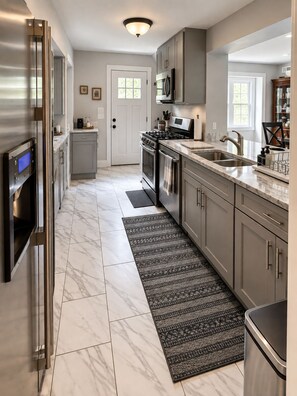 A modern kitchen with stainless steel appliances, grey cabinets, and a marble floor. - Spacious 4-bedroom house in amazing Great Falls (Great Falls)