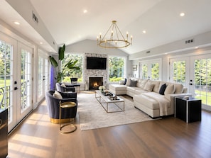 A spacious living room with a fireplace, a large sectional sofa, and a chandelier.