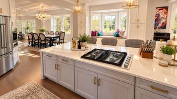 A modern kitchen with a large island, stainless steel appliances, and a dining area with a view.