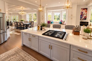 Een moderne keuken met een groot eiland, roestvrijstalen apparatuur en een eetgedeelte met uitzicht.