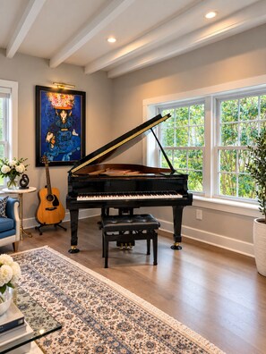 A grand piano in a well-lit room with large windows, a framed painting, and a guitar. - Spacious 4-bedroom house in amazing Great Falls (Great Falls)