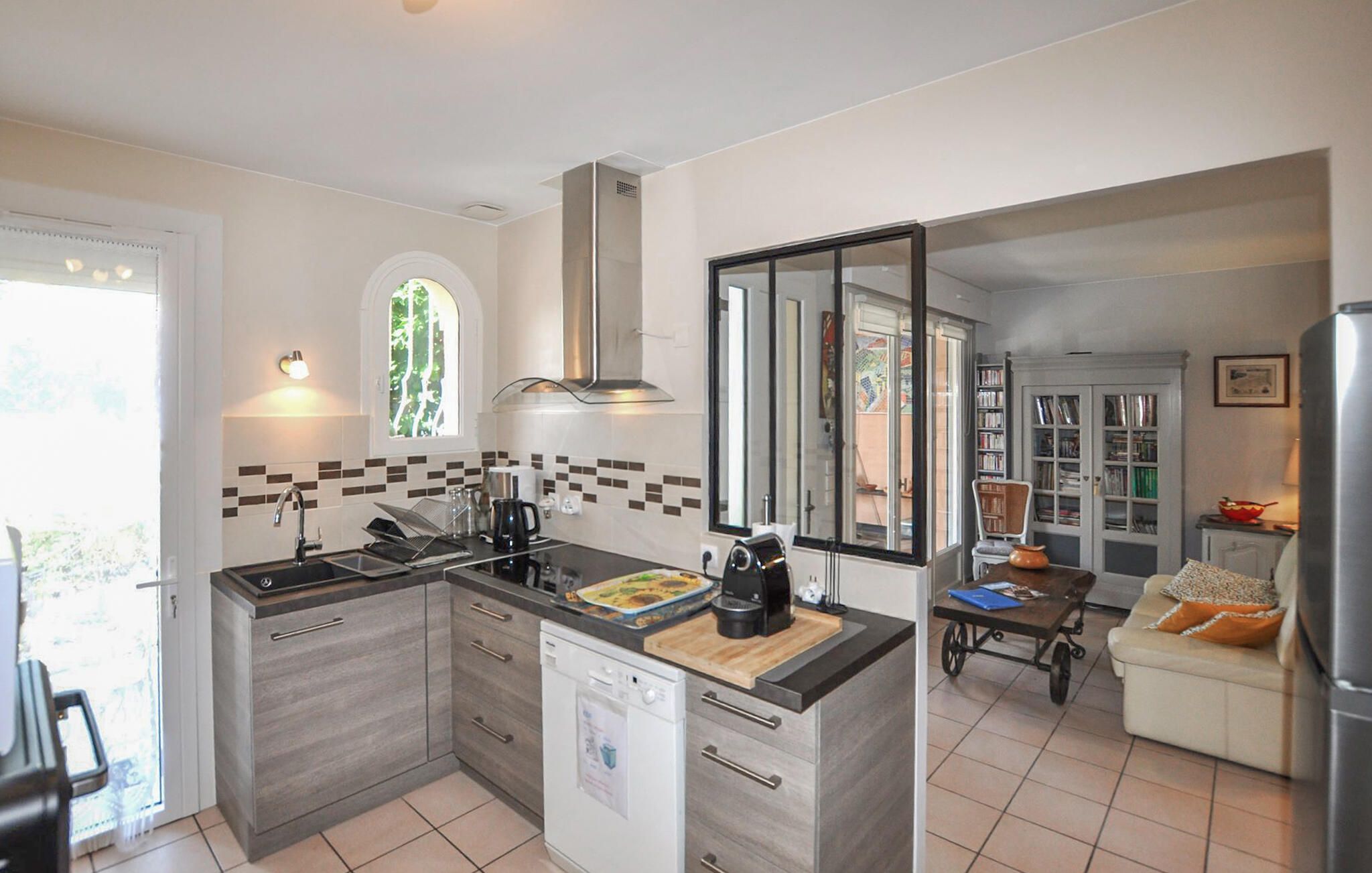 A modern kitchen with a dishwasher, a coffee machine, and a dining area with a table and chairs.