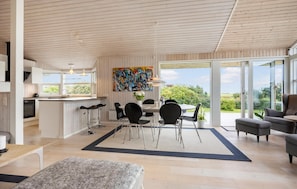 A modern kitchen with a dining area, large windows, and a view of the outdoors. - 3 bedroom stunning home in Bogense (Bogense)