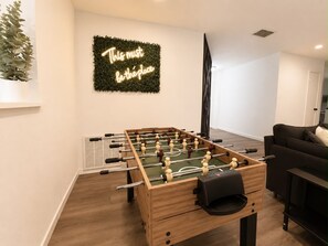 Ein Raum mit einem Tischkicker, einem an der Wand befestigten Schild und einer Pflanze.