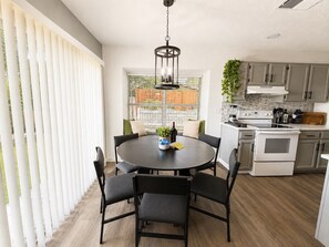 A modern kitchen with a dining area, featuring a round table, chairs, and a hanging light fixture. - The Grey Hideaway House - 5 Min to SeaWorld (San Antonio)