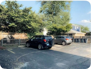 Ein Parkplatz mit zwei Autos, einem Zaun und einem Gebäude im Hintergrund.
