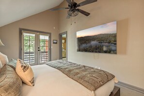 Ein Schlafzimmer mit einem Bett, einem Deckenventilator, Seeblick und einer Tür, die auf einen Balkon führt.