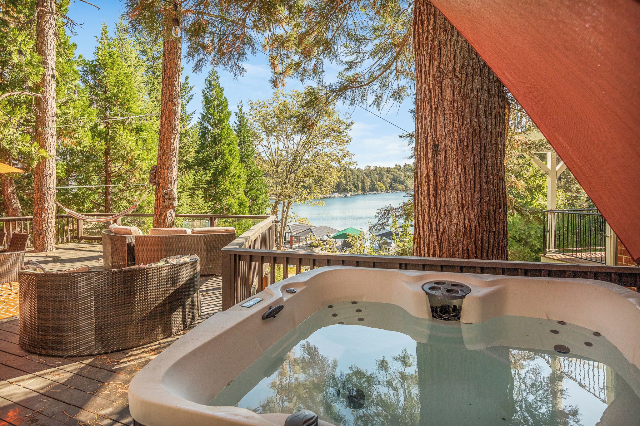 Un bain à remous avec vue sur un lac, entouré d’arbres et agrémenté de mobilier d’extérieur.