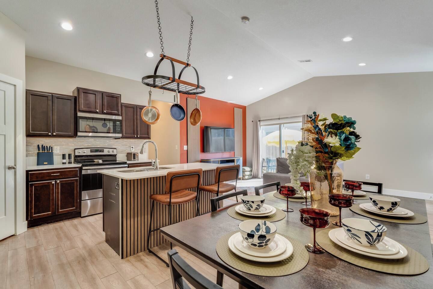 A modern kitchen with dark wood cabinets, a central island, and a dining area with a table set for four.