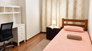 Une chambre à coucher comprenant un lit, un bureau, une chaise, une table de chevet et une lampe.