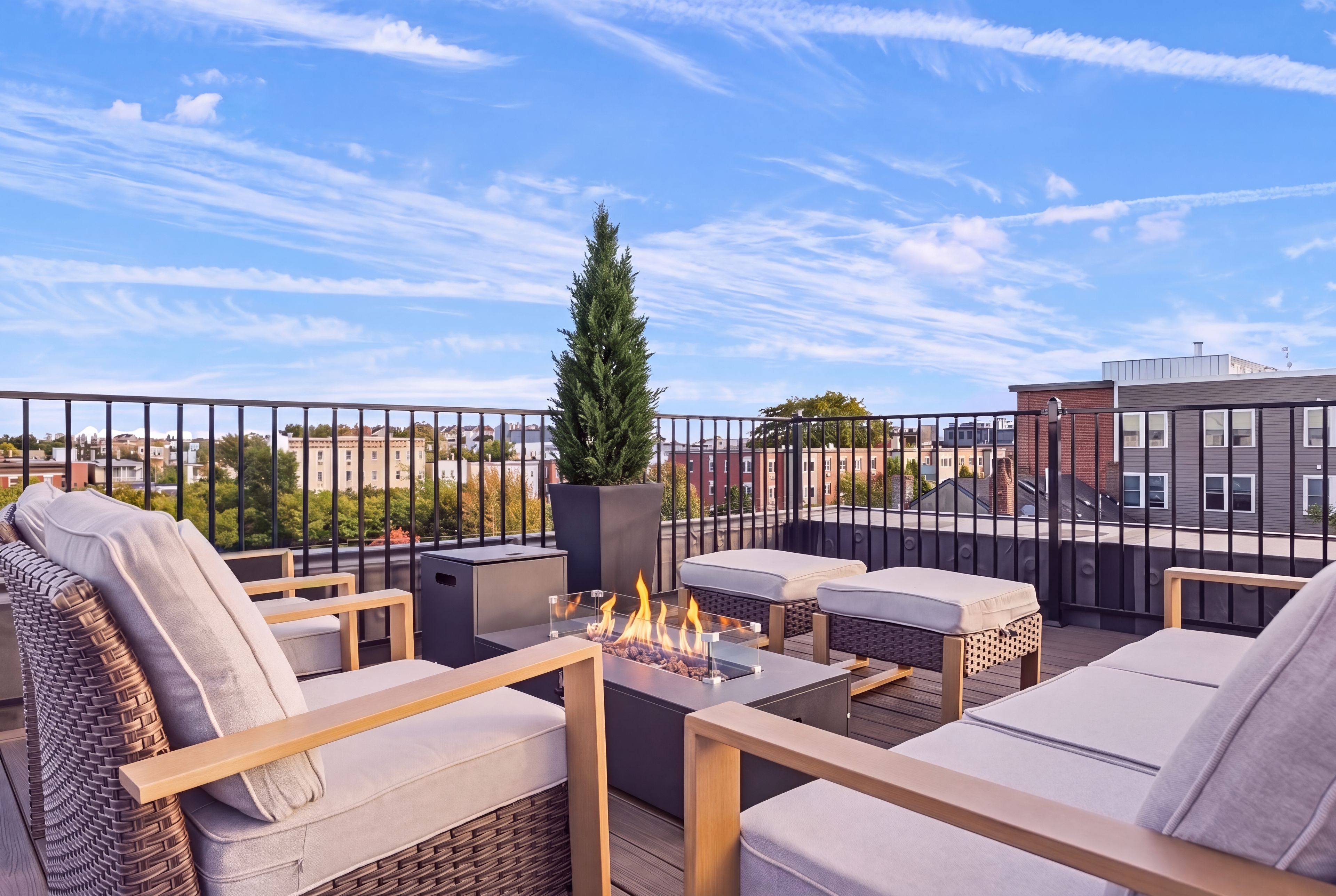 A rooftop terrace with outdoor seating, a fire feature, and a view of the cityscape.