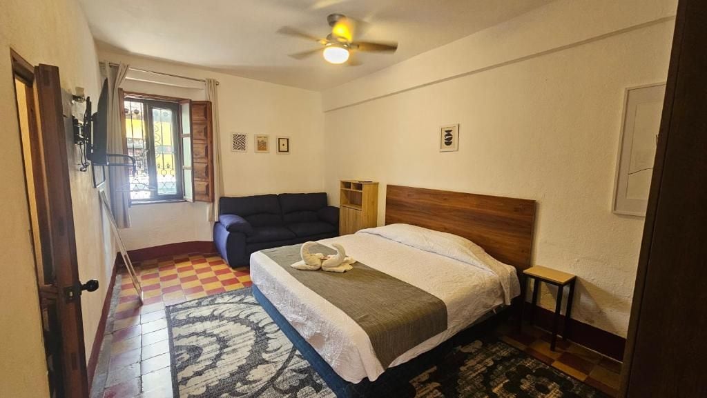 A bedroom with a bed, a ceiling fan, a window, and a door.