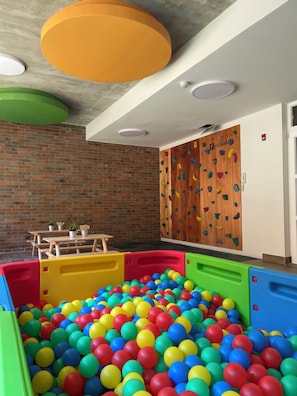 A children's play area with a ball pit, climbing wall, and wooden tables. - Edificio Rosas by Domus Travels (Santiago)