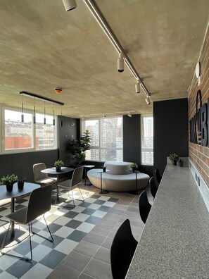 A modern interior with a checkered floor, a seating area with a sofa and chairs, and a bar counter. - Edificio Rosas by Domus Travels (Santiago)