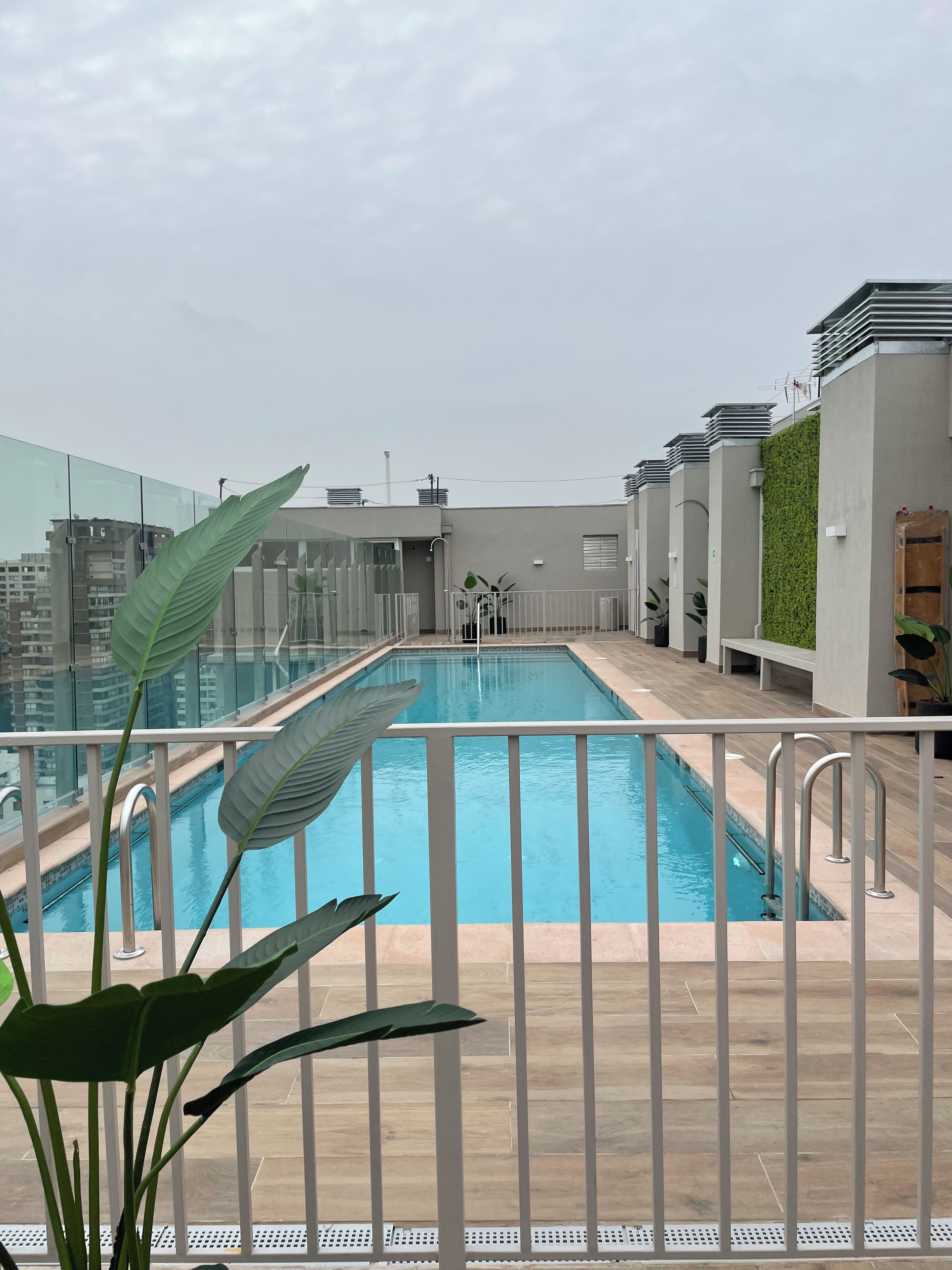 A rooftop swimming pool with a view of surrounding buildings.