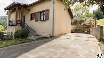 Une maison à deux étages avec un escalier en béton menant à l’entrée, une clôture en bois et une allée pavée.