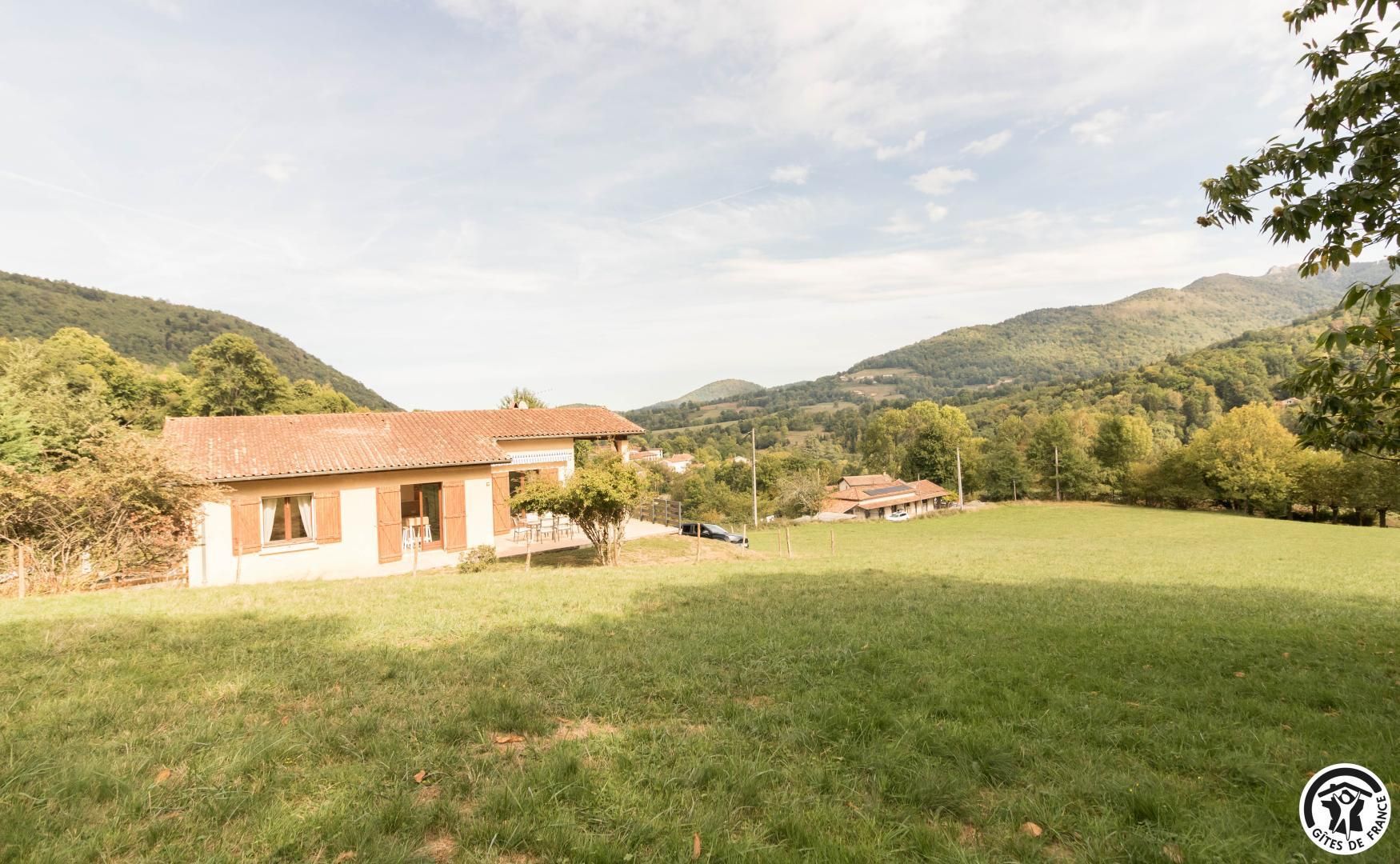 Une propriété rurale comprenant une maison de plain-pied, une cour clôturée et une vue sur des collines ondulantes.