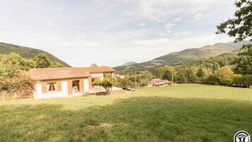 Une propriété rurale comprenant une maison de plain-pied, une cour clôturée et une vue sur des collines ondulantes.