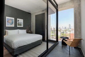 A modern bedroom with a large bed, a glass door leading to a balcony, and two framed pictures on the wall. - w *| Cozy 1BR in Lively Tabacalera (Ciudad de México)