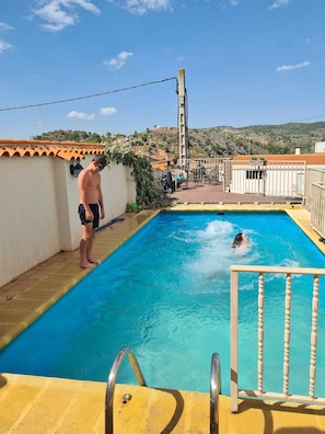 A swimming pool with a ladder, a person swimming, and another standing by the poolside. - Tranquil Mountain Retreat With Private Pool in Quesa, Valencia (Quesa)