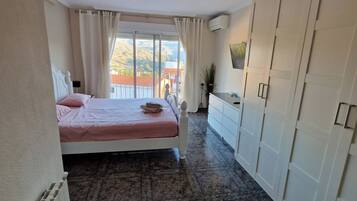 A bedroom with a bed, a dresser, and a view of the outdoors.