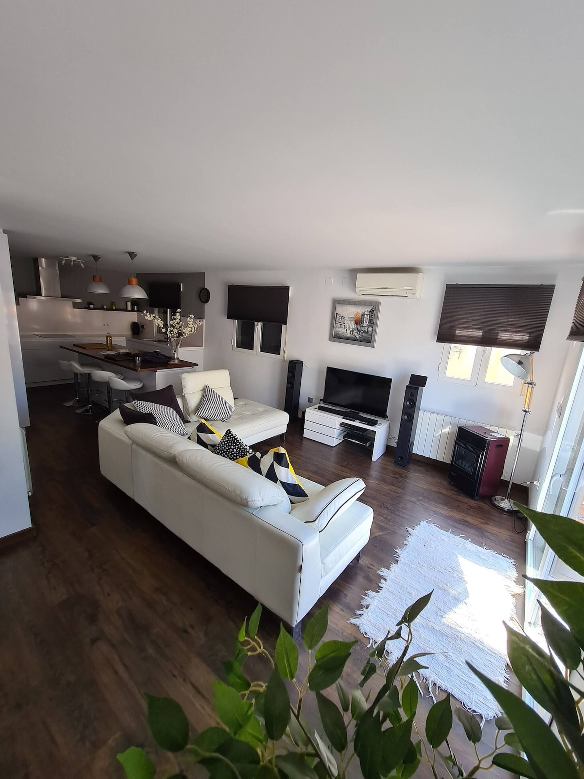 A modern living room with a white sofa, a flat-screen TV, and a fireplace.