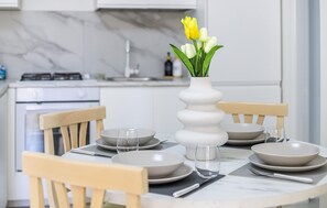A dining table set with plates, glasses, and cutlery, with a vase of flowers in the center. - Stunning apartment in Marina di Ragusa with WiFi (Marina di Ragusa)