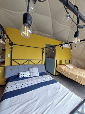 Un dormitorio con dos camas, un ventanal grande y una estructura de techo tipo tienda de campaña.