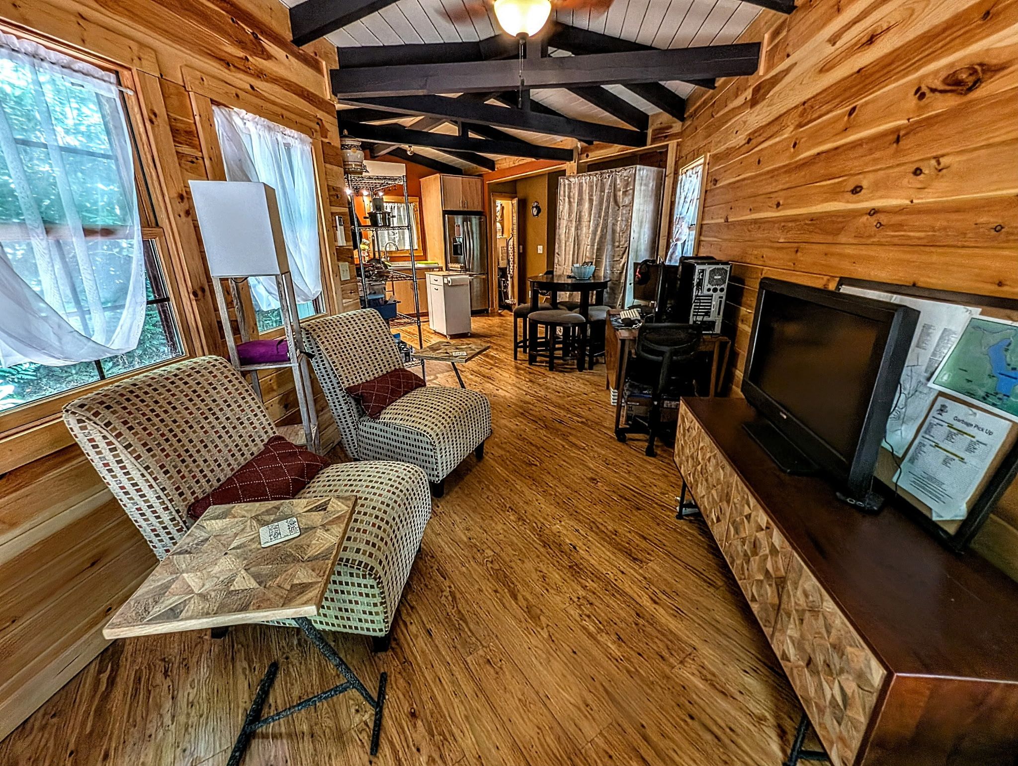 A cabin interior with a dining area, seating, a kitchen, and a television.