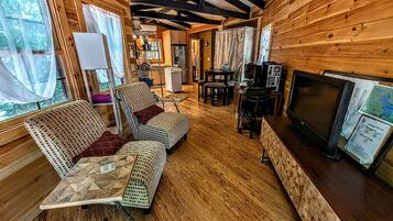 A cabin interior with a dining area, seating, a kitchen, and a television.