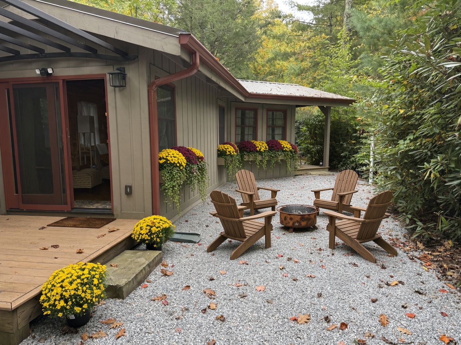 A covered outdoor seating area with Adirondack chairs and a fire pit, surrounded by a gravel patio and a wooden deck.
