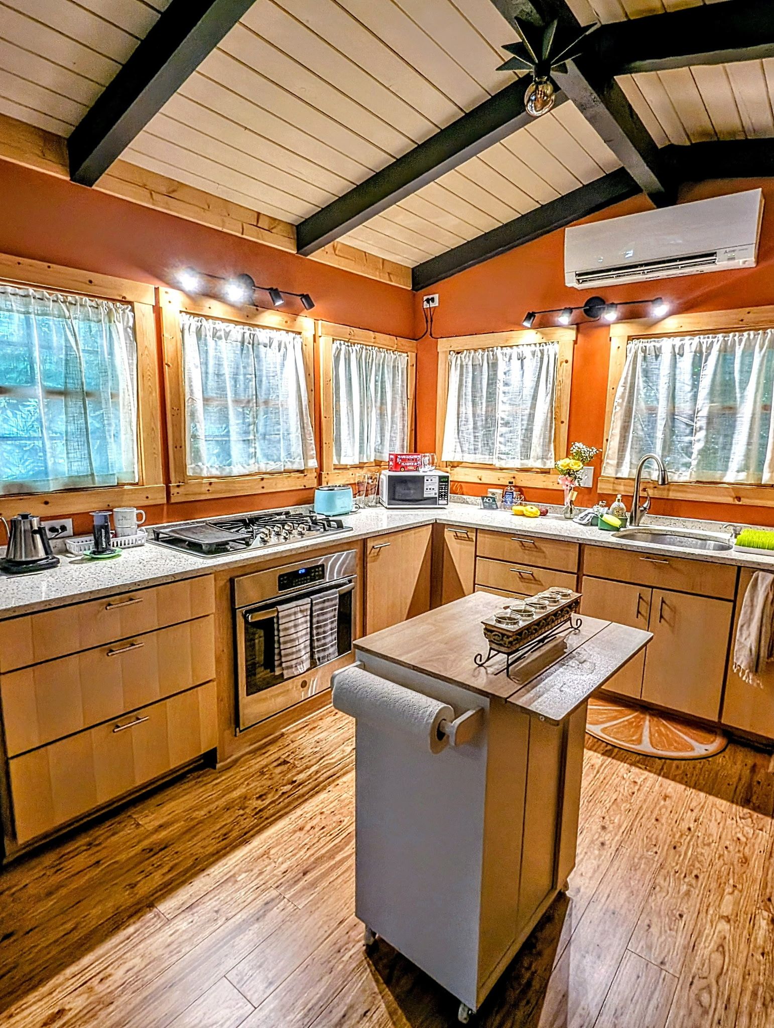 A kitchen with wooden cabinets, a central island with a sink, and a stove.