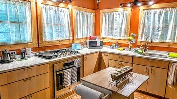 A kitchen with wooden cabinets, a central island with a sink, and a stove.