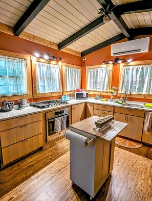 Une cuisine avec des meubles en bois, un îlot central doté d’un évier et une cuisinière.