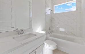 A bathroom with a bathtub, toilet, and a large mirror. - Villa Reflection-newly built on water, west facing, pool and spa (Cape Coral)