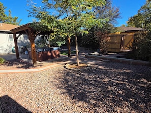 A backyard with a patio, a hot tub, and a wooden fence. - 3 BED Home w/Hot Tub & Grill (Colorado Springs)