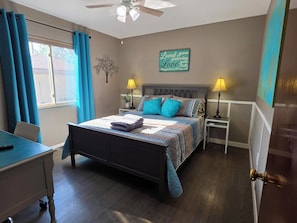 A bedroom with a bed, two bedside tables, a desk, and a window with curtains. - 3 BED Home w/Hot Tub & Grill (Colorado Springs)