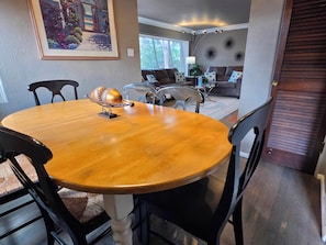 A dining area with a wooden table and chairs, a decorative fruit bowl, and a painting on the wall. - 3 BED Home w/Hot Tub & Grill (Colorado Springs)