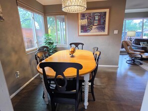 A dining area with a wooden table and black chairs, a chandelier, and a painting on the wall. - 3 BED Home w/Hot Tub & Grill (Colorado Springs)