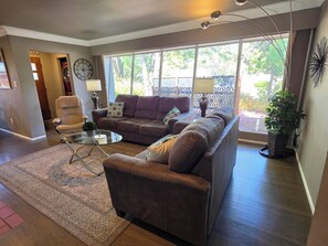 A living room with a brown leather sofa, a glass coffee table, and a patterned rug. - 3 BED Home w/Hot Tub & Grill (Colorado Springs)