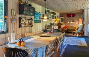 A dining area with a wooden table, chairs, and a patterned tablecloth. There are cabinets with glass doors and various decorative items on the walls. - 4 bedroom nice home in Løgstør (Løgstør)