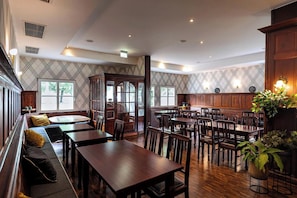Un comedor amplio con mesas y sillas de madera, un banco empotrado con cojines, y grandes ventanas que dejan entrar luz natural.