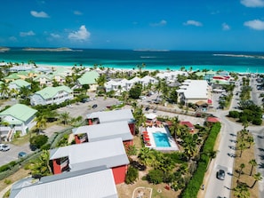 Luchtbeeld van een resort met meerdere gebouwen, een zwembad en een strand.